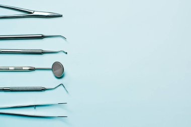 Diş hekimi araçları ışık üzerinde mavi arka plan: corncang, küret, diş sonda, brüt-mayer kelepçe, diş ayna ve explorer. Dişlerle ilgili sağlık bilgisi ve sağlık kavramı.