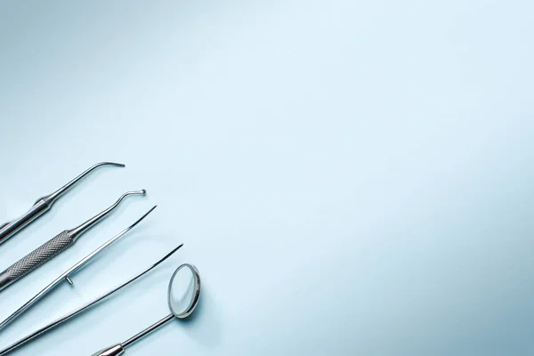 Dentist tools on blue background: dental probe, forceps dental mirror and explorer. Dental hygiene and healthcare concept. Copy space. — Stock Photo, Image