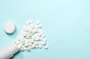 Tablet veya hap masanın üzerinde beyaz bir şişe dışında bırakın. Tıp kavramı.