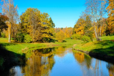 Güzel sonbahar güneşli manzara Slavyanka Nehri ile Pavlovsk park ve ağaçlar ile kırmızı ve turuncu yaprak, Pavlovsk, St Petersburg.