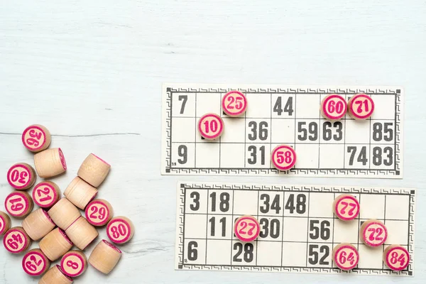 Board game lotto or bingo. Many wooden lotto barrels with numbers and card on white table during a game. Vintage game, Russia.