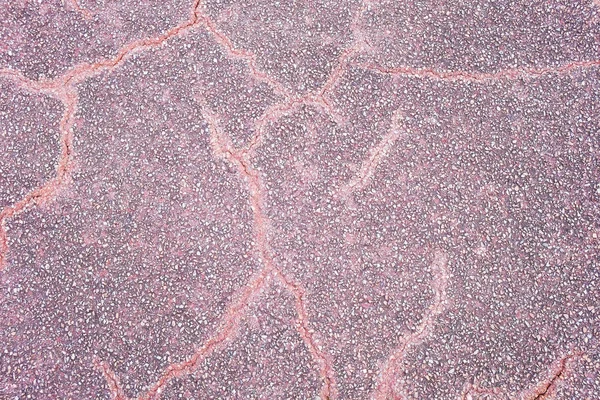 Purple asphalt pavement texture background with cracks. Close up with small stones for design.