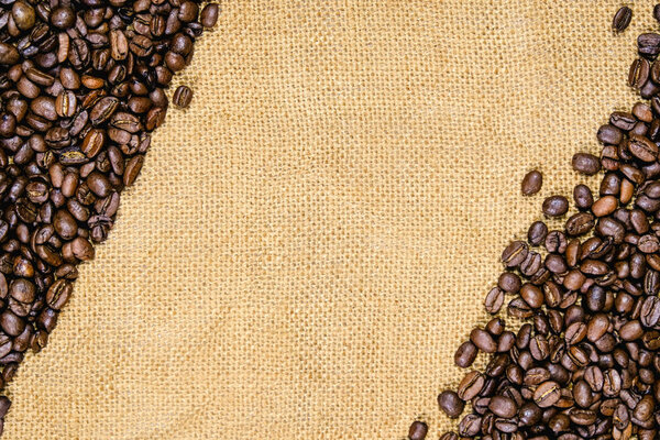 Vintage coffee background. Roasted coffee beans on real jute burlap.