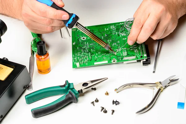 De technicus elektronica vervangt de niet-werkende element van het elektronische apparaat met een soldeerbout. De handen van een ingenieur elektronica, reparatie elektronische apparaten concept. — Stockfoto