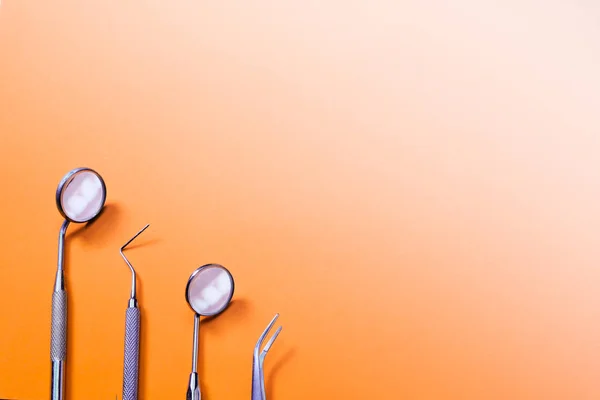 Dentist tools: two mirrors, explorer and tweezers on orange gradient bacrground. — Stock Photo, Image