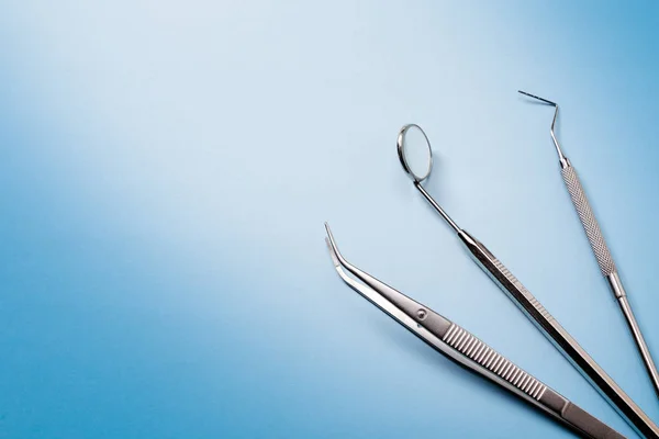 Dentist tools: mirror, dental explorer and tweezers in right on blue gradient background. — Stock Photo, Image