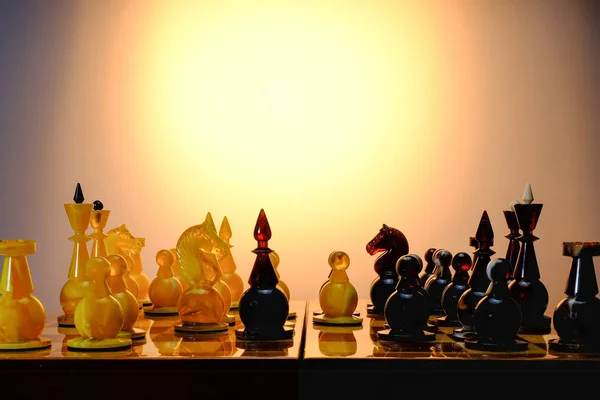 Chess game with amber chess pieces on the board. With gradient gold background.