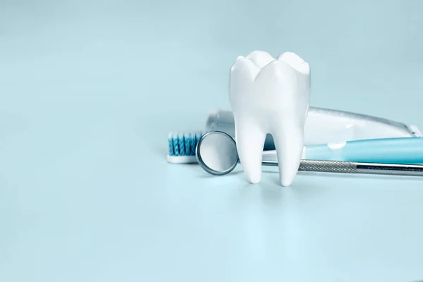 White big healthy tooth, toothbrush and toothpaste for dental care, on light blue dental background. — Stock Photo, Image