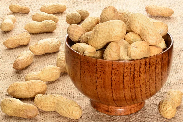 Grondnoten. Droge noten in bamboe kom met enkele peants op de bruine houten tafel. — Stockfoto