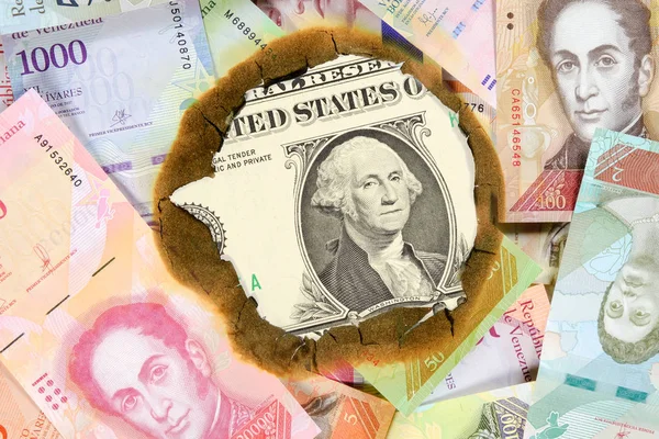 Venezuela hiperenflasyon kavramı. Farklı bolivar değerinde yanmış Venezuela banknotları, yanmamış bir dolarlık banknotu görebileceğiniz delikten. Yakın çekim — Stok fotoğraf