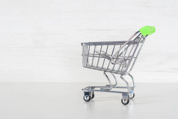 Shopping cart with light green handler. Market stroller on a light grey background.