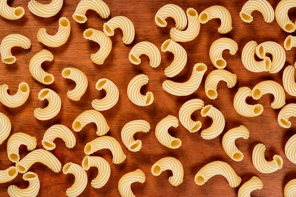 Dry uncooked cavatappi italian pasta on brown wood background. — Stock Photo, Image