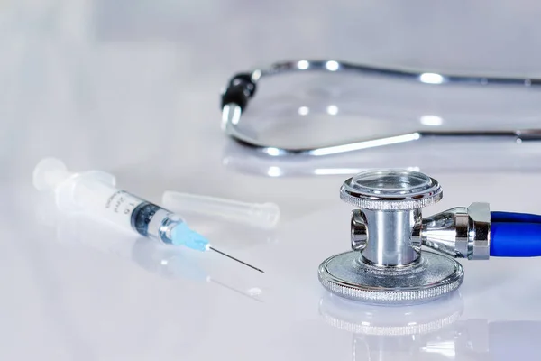 Estetoscópio ou fonendoscópio em uma mesa branca de médicos com seringa. Tratamento do frio ou da gripe . — Fotografia de Stock