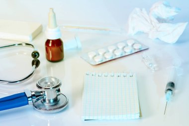 Şırınga, nosal sprey, ilaçlar ve mendil ile bir doktorun beyaz masasında Stetoskop veya fonnkop. Soğuk algınlığı veya grip tedavisi