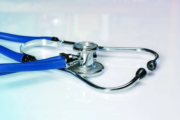 Stetoskop lub fonendoskop na białym biurku lekarza z błyszczącą powłoką. Leczenie koncepcji zimna lub grypy. — Zdjęcie stockowe