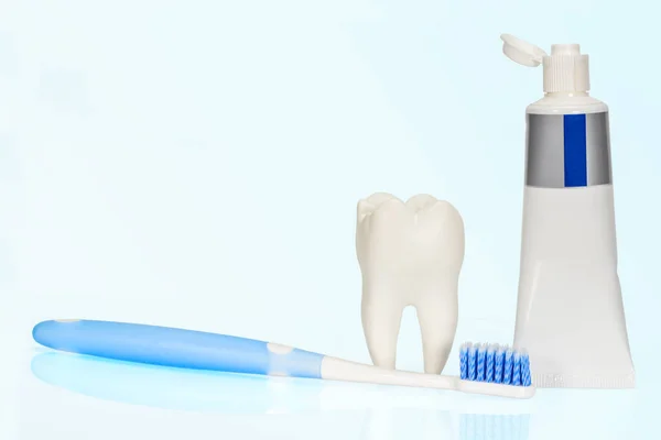White big health tooth, toothbrush and toothpaste for dental care, on light blue dental background. — Stock Photo, Image