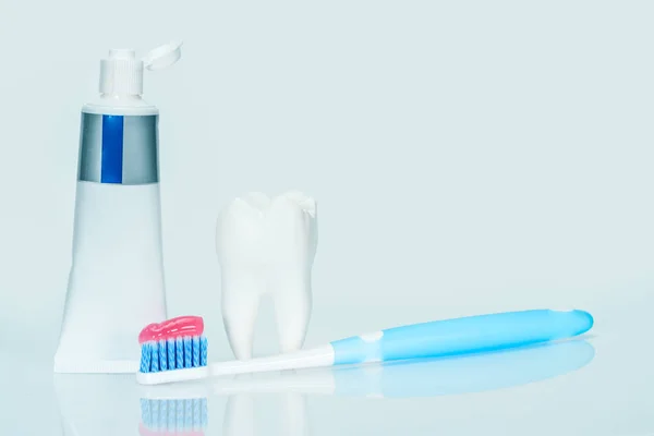 White big health tooth, toothbrush and red toothpaste for dental care, on light blue dental background. — Stock Photo, Image