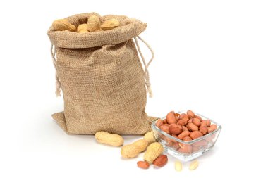 Fıstık. Bazı soyulmuş çekirdekleri ile fıstık ve cam kase dolu Jüt çuval, gölgeler ile beyaz arka plan üzerinde izole.