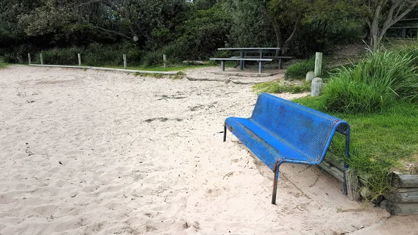 Una panchina blu acciaio sulla sabbia — Foto Stock