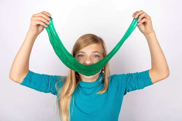 stock image Smiling girl holding a long green slime toy in front of her face and making a smile with it