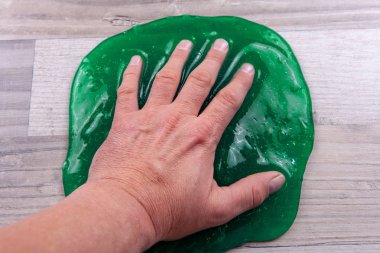 Hand squeezing a slime toy on a table clipart