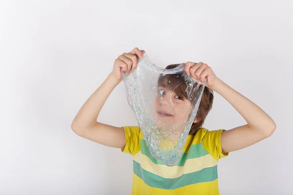 Cheerful boy holding a  slime and looking through its hole. — Stock Photo, Image