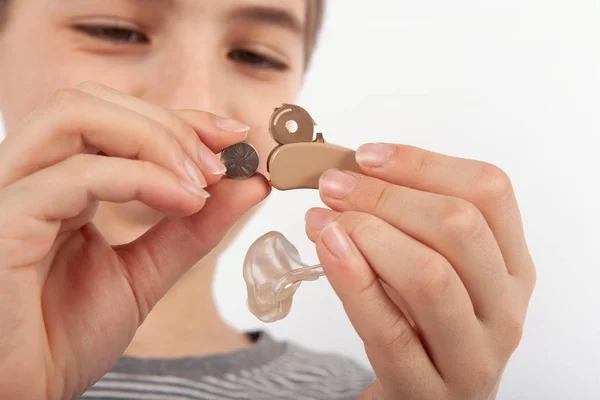 Close up of a young boy's hands replacing a battery of a hearing aid — Stock Photo, Image