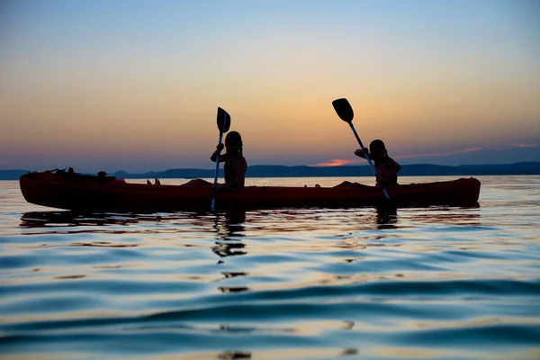 Silhouette de jeunes filles kayak après le coucher du soleil au lac Balaton . — Photo