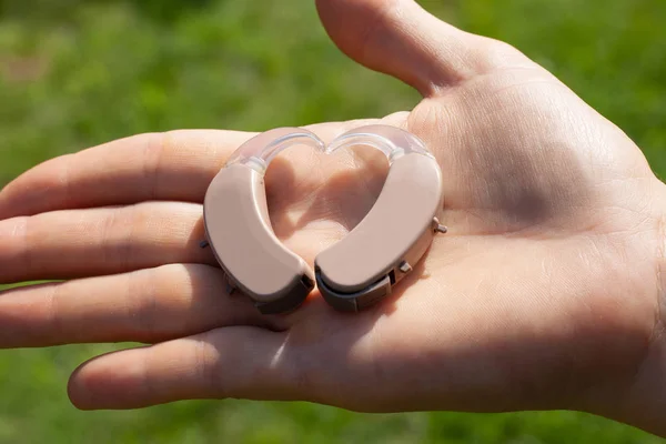 Primer plano de los audífonos en forma de corazón en una palma con un —  Fotos de Stock