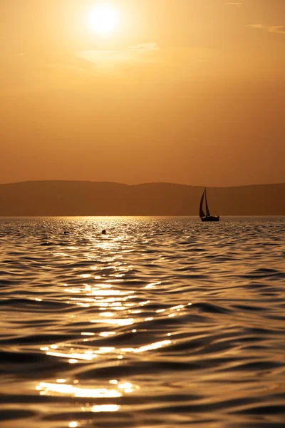 Puesta de sol sobre el lago Balaton con una silueta de velero en Hungría . — Foto de Stock