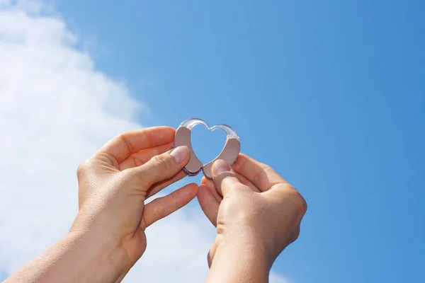 Vrouwen handen tonen hart met gehoorapparaat — Stockfoto