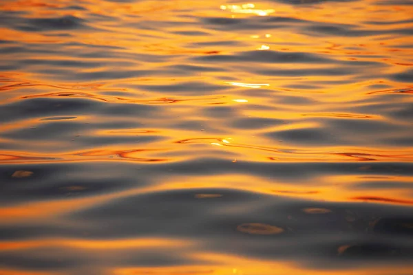 Superficie natural de agua con olas de color dorado al atardecer Imagen de stock