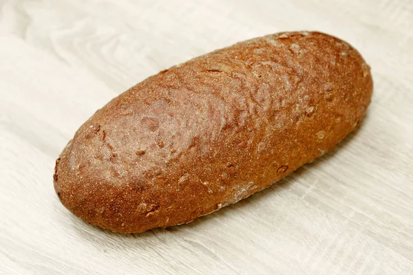 En svart bröd på en trä bakgrund — Stockfoto