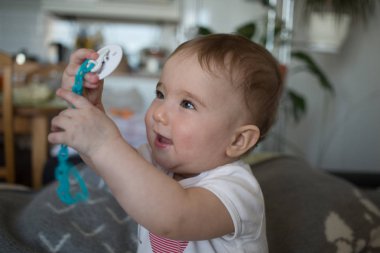 Çocuk sevinçle bir zincir bir emzik ile tutar.