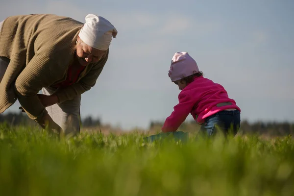 Grandmother and little granddaughter working in the field — Stock Photo, Image