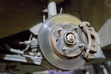 garajda tamir altında arabanın eski ve paslı fren diski