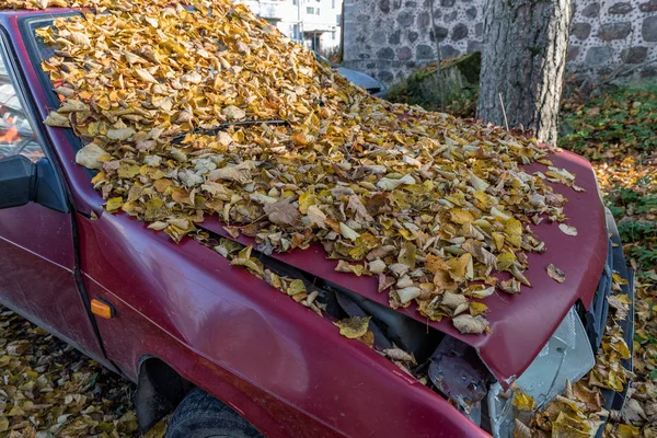 Oude gebroken auto bezaaid met herfst bladeren — Stockfoto