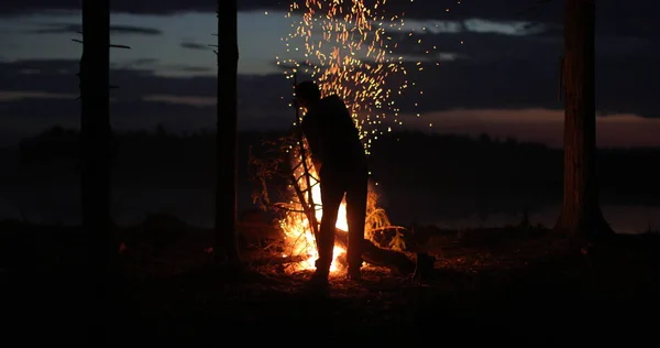 Silhouette eines Mannes am Feuer in der Nacht gegen den Himmel — Stockfoto