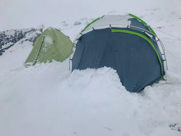 tents in extreme winter conditions covered with snow high in the mountains