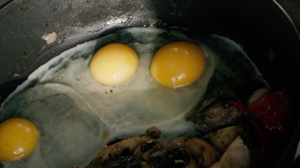 Куриные яйца с картофелем и овощами, жарящимися на сковороде — стоковое видео