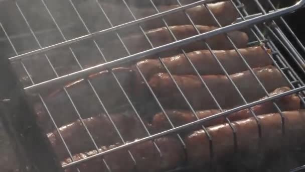 Колбасы на гриле, жарящиеся на углях — стоковое видео