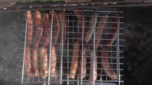 Saucisses de viande sur le gril rôtissant sur les charbons — Video