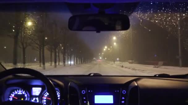 Οδήγηση σε ένα αυτοκίνητο στη νυχτερινή πόλη το χειμώνα. θέα από την καμπίνα — Αρχείο Βίντεο