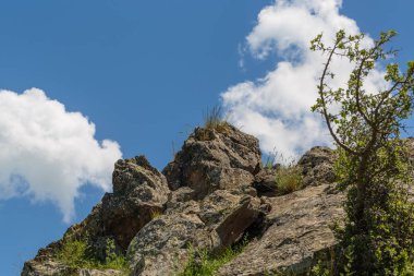 mavi gökyüzüne karşı taş tepe ve bulutlar aşağıdan yukarıya doğru görünümü