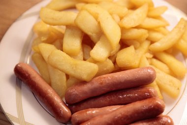 bir tabakta kızarmış sosis ile kızarmış patates yakın