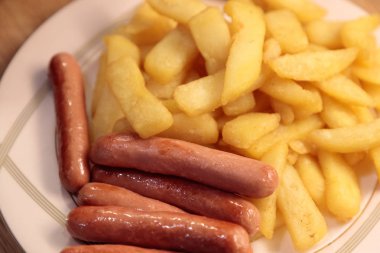 bir tabakta kızarmış sosis ile kızarmış patates yakın