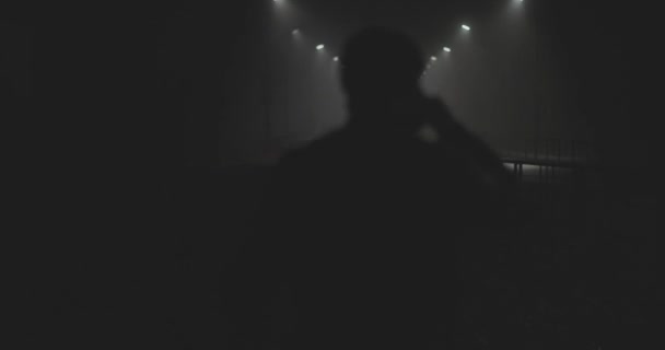 Silhouette of a man from the back in a foggy night city — Stock Video