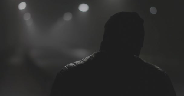 Sziluettje egy férfi a hátán egy ködös éjszakai város — Stock videók