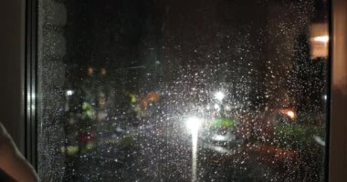 yağmurda çok katlı bir binanın penceresi gece sokağa bakan damla