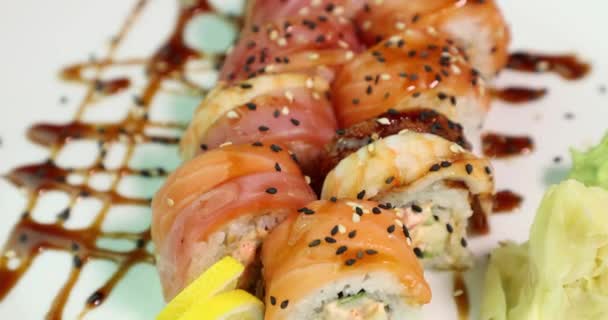 Аппетитные суши на белой тарелке вращаются вокруг ее оси вид сверху — стоковое видео